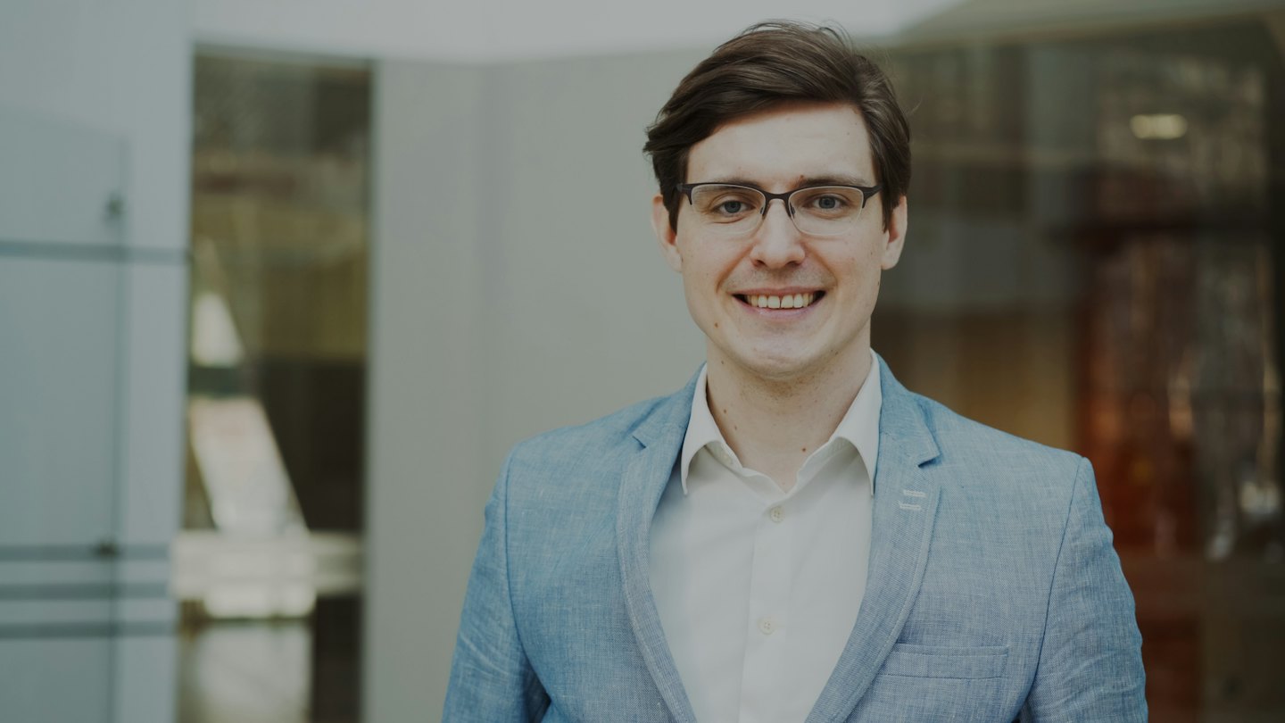 Man in a blue blazer smiling in an office.