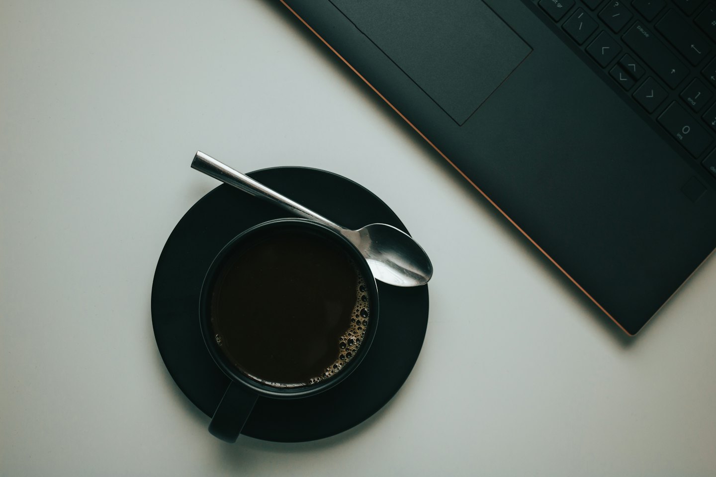 Overhead view of a coffee cup and laptop on a desk.