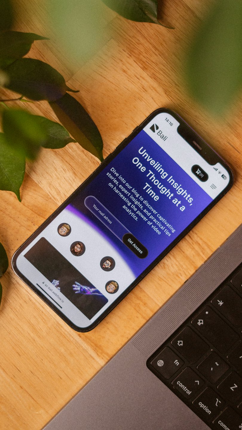 Smartphone with a blog sign-up form resting on a wooden desk.